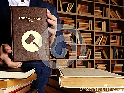 PERSONAL INJURY LAW book in the hands of a jurist. Personal injury law, also known as tortÂ law, is designed to protect you if Stock Photo